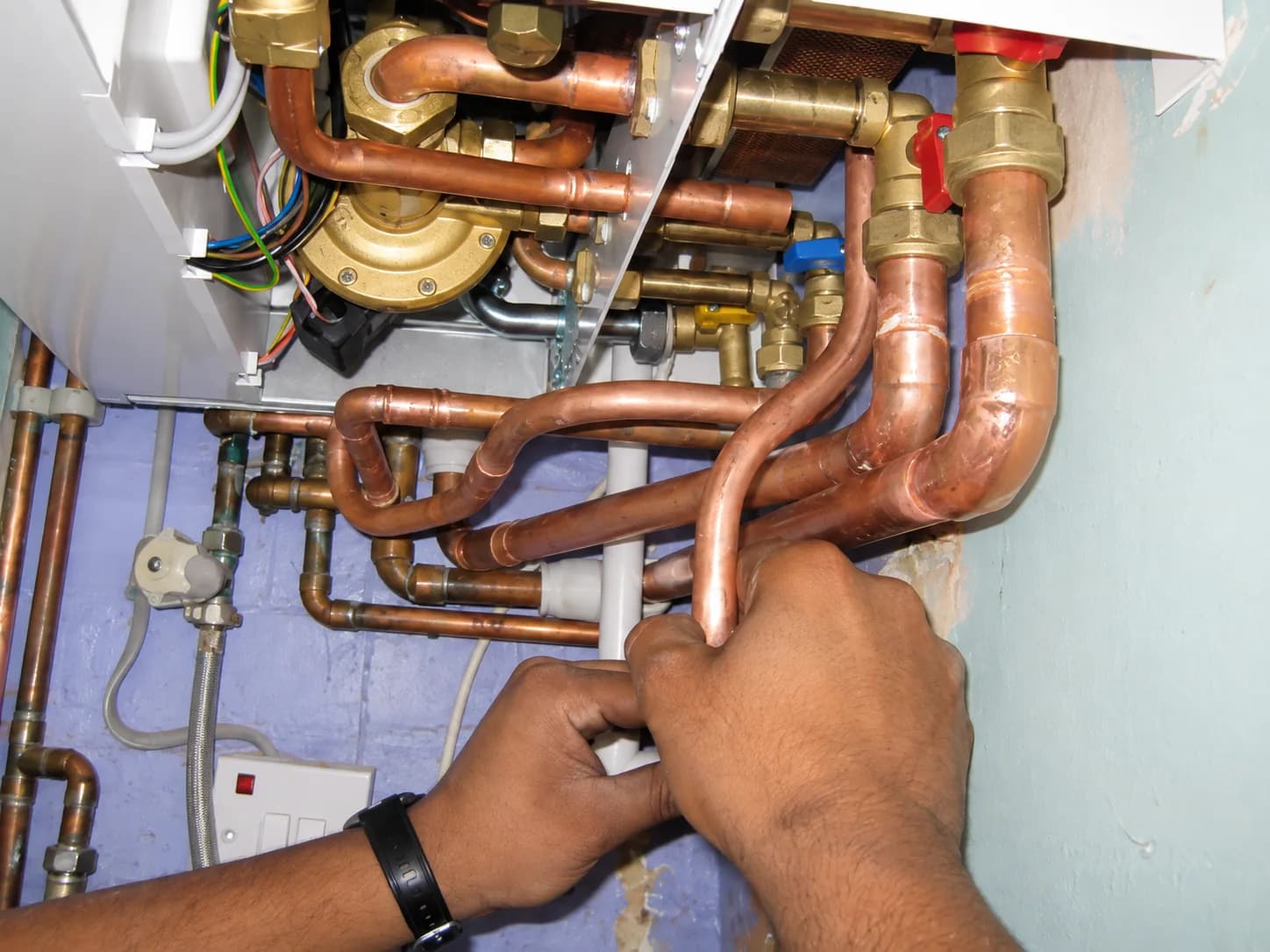 Carlton Fuller working on copper pipework beneath a boiler